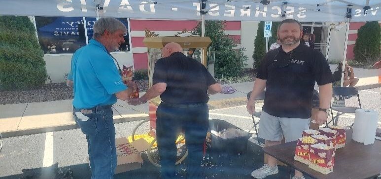 Three men handing out popcorn.